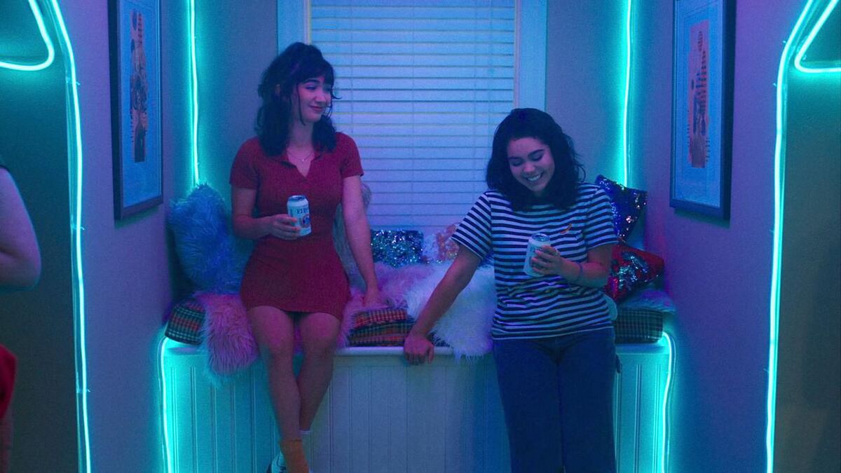 Page (Rowan Blanchard) and AJ (Auli'i Cravalho) in a room illuminated by the neon lights of the crash (2022)