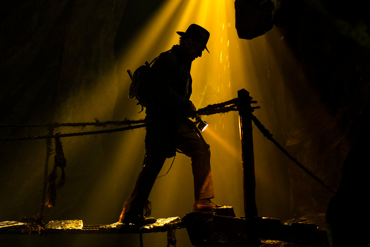 Indiana Jones crosses a bridge in shadow in a still from the untitled Indiana Jones 5 movie