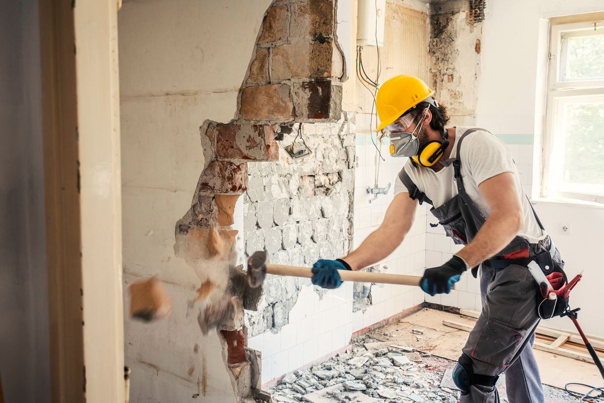 Using a sledgehammer to knock down an interior wall. 
