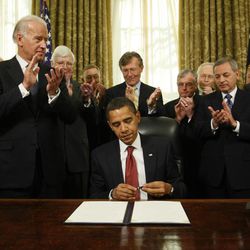 FILE - In this Jan. 22, 2009, file photo, President Barack Obama caps his pen after he signed an executive order closing the prison at Guantanamo Bay in the Oval Office of the White House in Washington. Vice President Joe Biden, second from left, and retired military officers applaud.