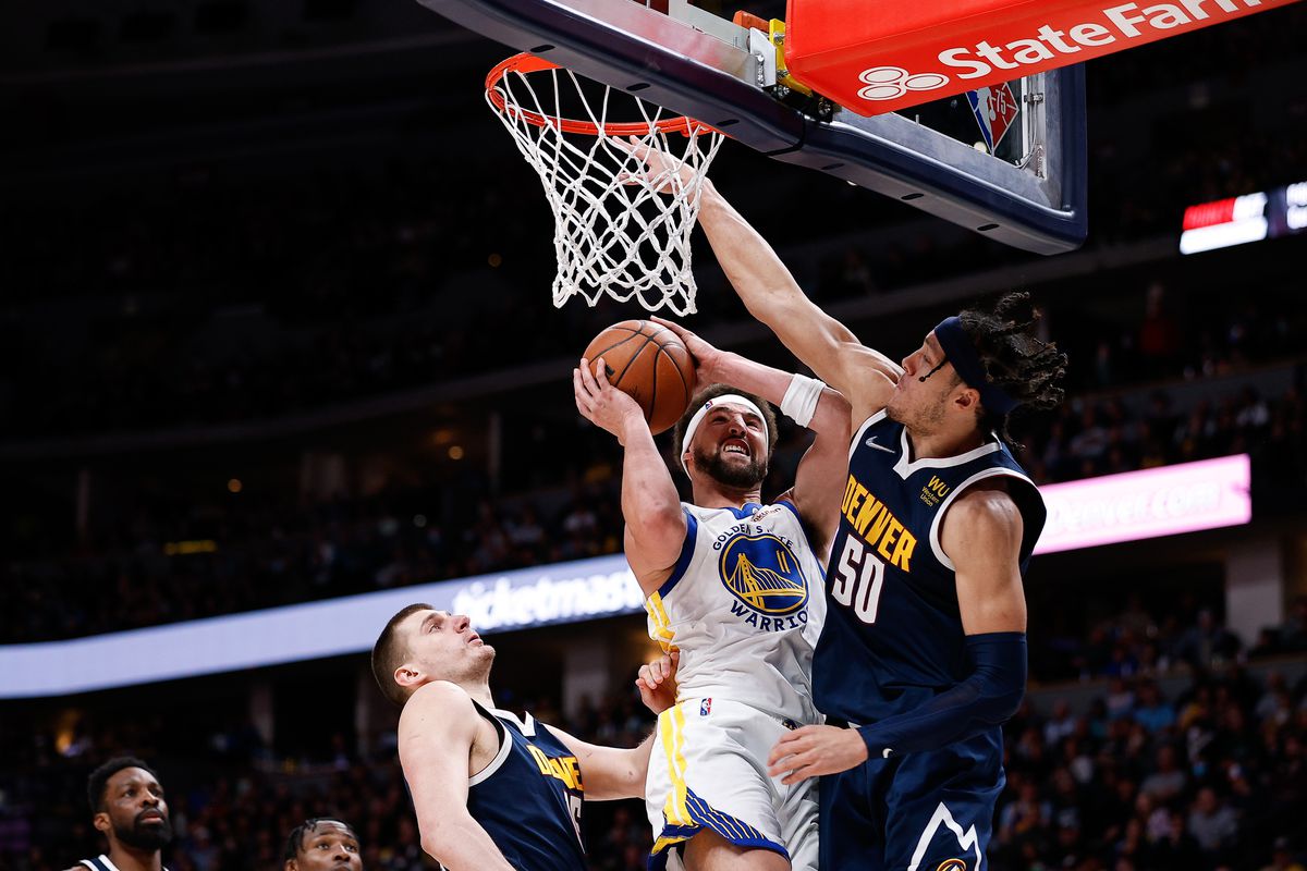 Golden State Warriors guard Klay Thompson (11) drives to the basket against Denver Nuggets forward Aaron Gordon (50) as center Nikola Jokic (15) defends in the fourth quarter at Ball Arena.&nbsp;