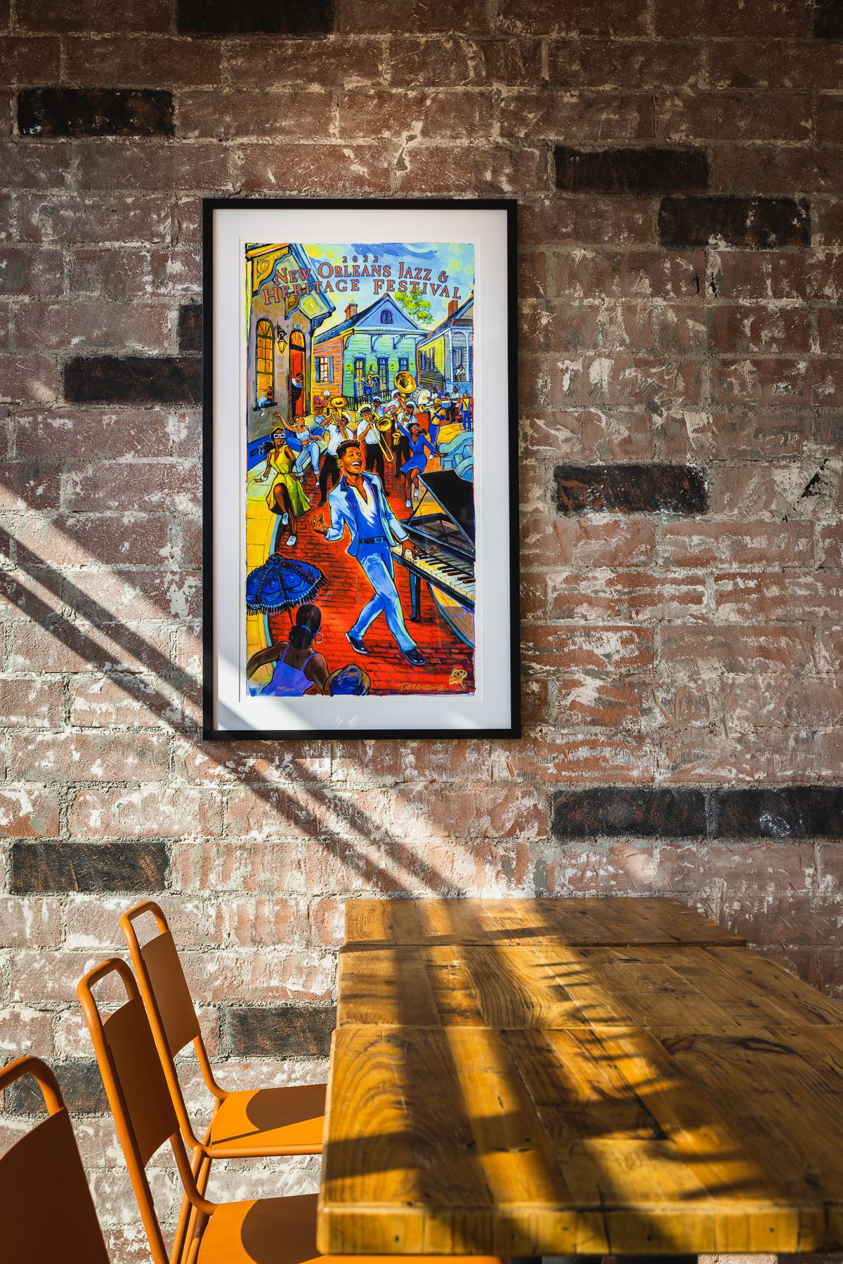 Afternoon light pours into a brick room with colorful art on the wall.