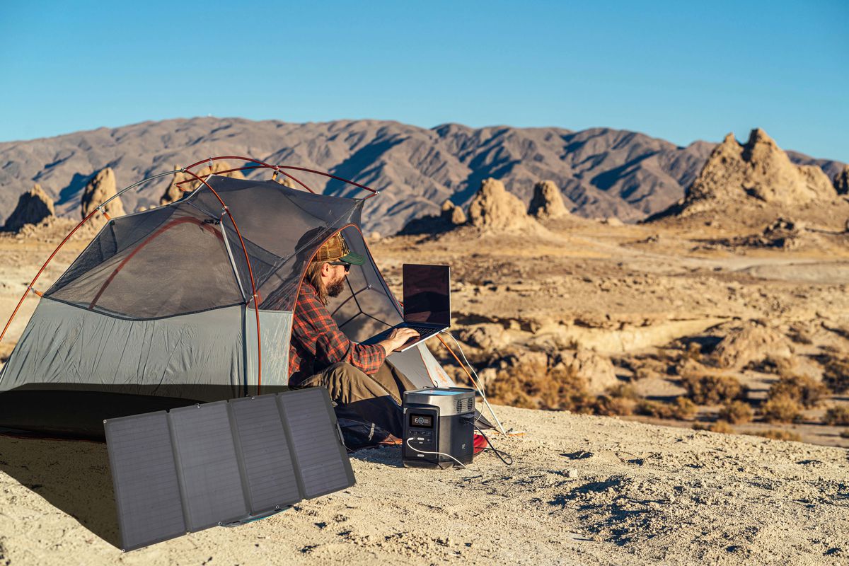 Man off-the-grid camping with power station and laptop 