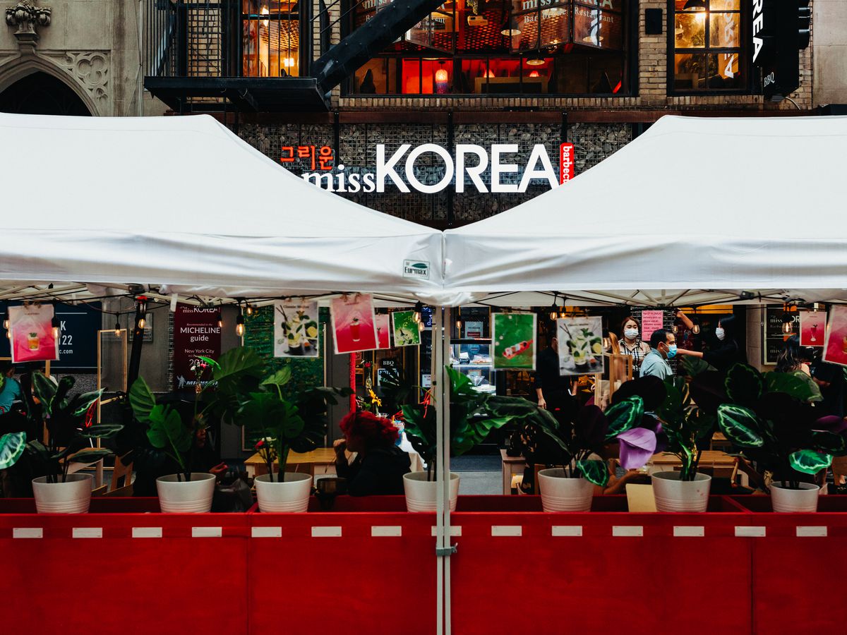 A tented outdoor setup is situated in front of a Korean barbecue restaurant, Miss Korea BBQ.
