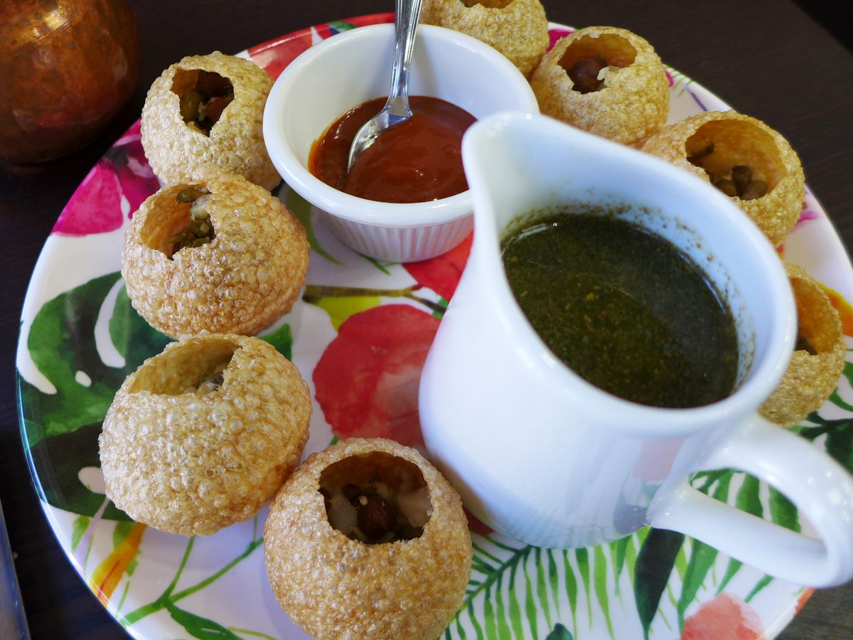 A ring of small cracker globes surrounds a pair of condiments, one thick like ketchup, the other in a small pitcher...