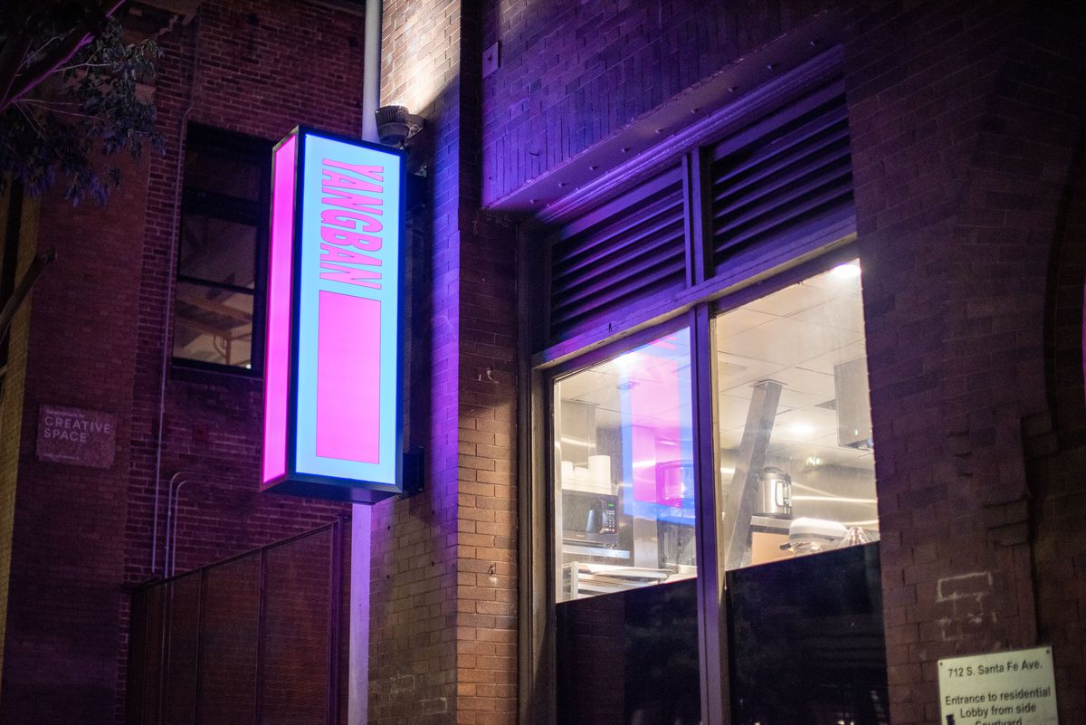 Neon signage for a new restaurant shown from the corner, at night.
