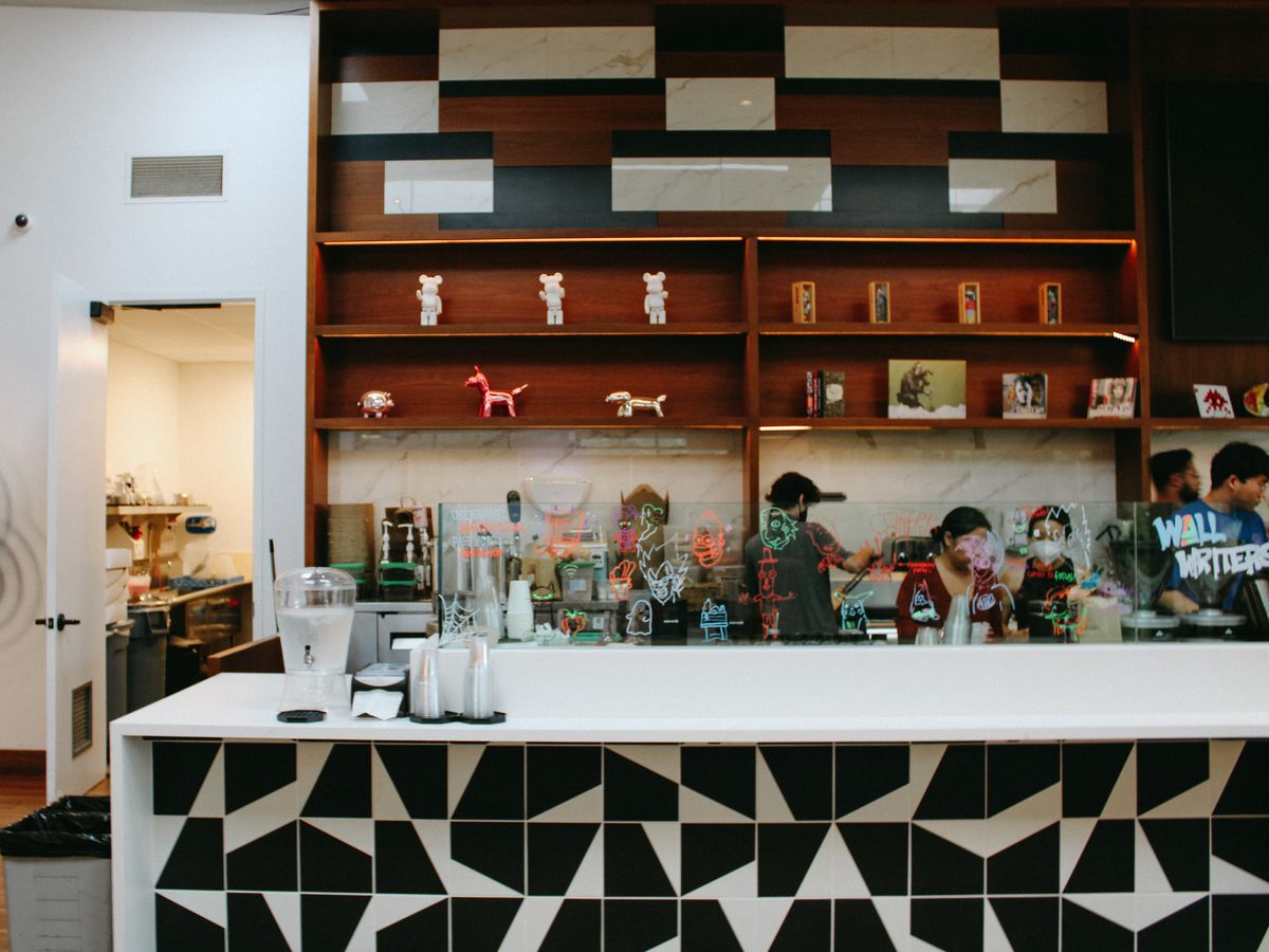 A coffee counter and shelves with pop art statues at Wall Writers.