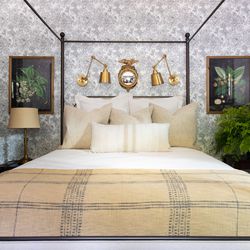 A metal four-poster dominates the downstairs guest room, which Alexandra wallpapered herself. She wants visitors to feel like they are on vacation when they stay here.