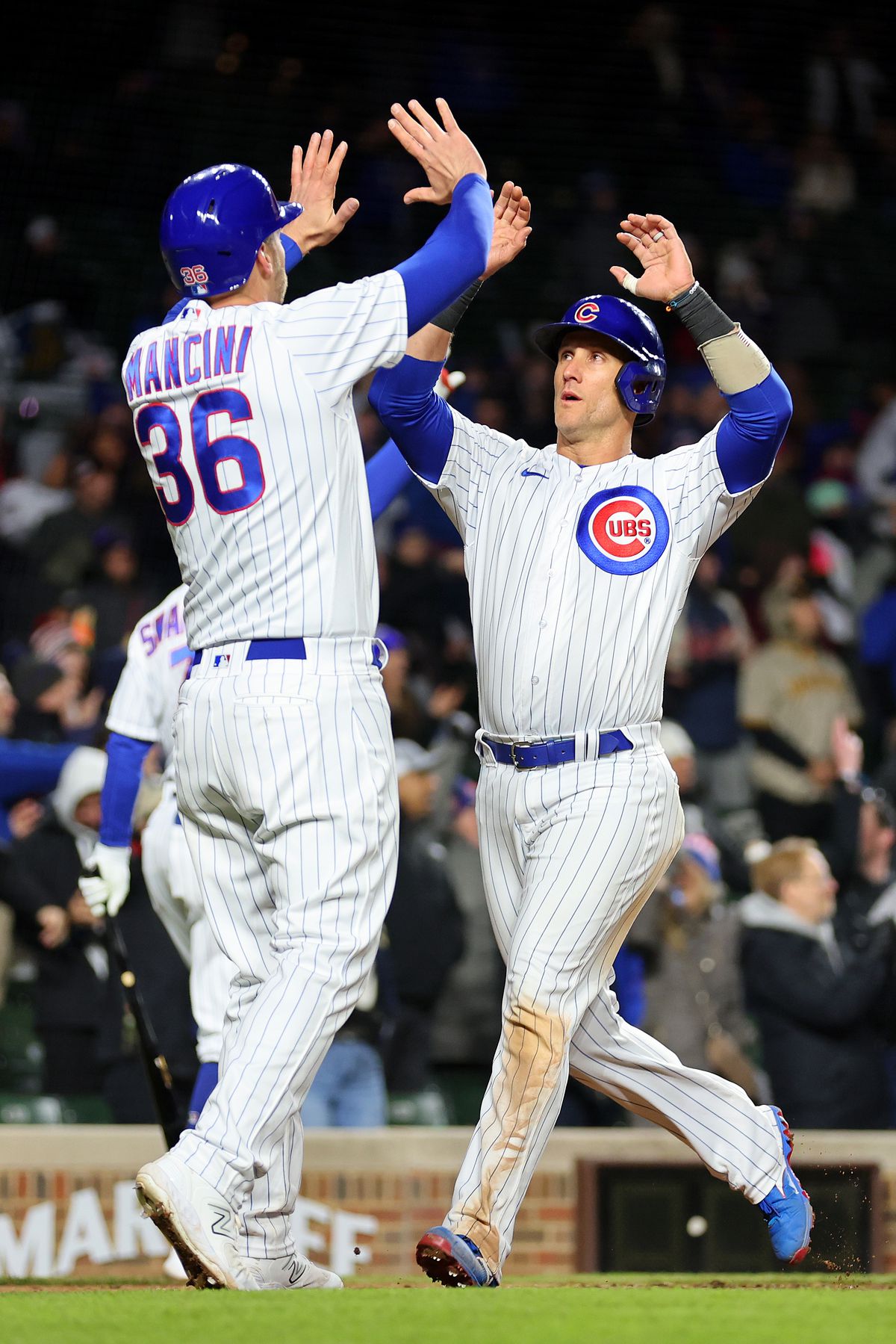 Yan Gomes #15 and Trey Mancini #36 of the Chicago Cubs celebrate after scoring a run on a three-RBI triple by Nico Hoerner #2 (not pictured) during the eighth inning against the San Diego Padres at Wrigley Field on April 25, 2023 in Chicago, Illinois.