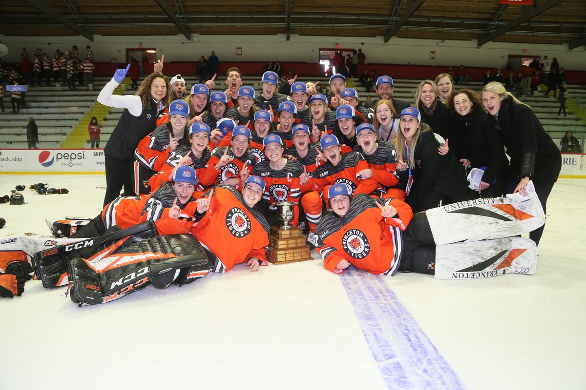 Princeton’s players, coaches, and staff members pose on the ice with the ECAC Championship trophy following their 3-2 overtime victory over Cornell.
