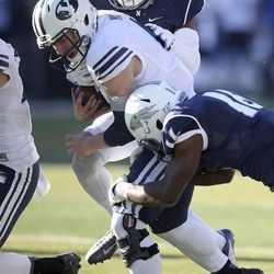 BYU's Taysom HIll, center, is tackled by Nevada's Markus Smith, back, and Kaodi Dike (16) during the second half of an NCAA college football game in Reno, Nev., on Saturday, Nov. 30, 2013. BYU won 28-23.