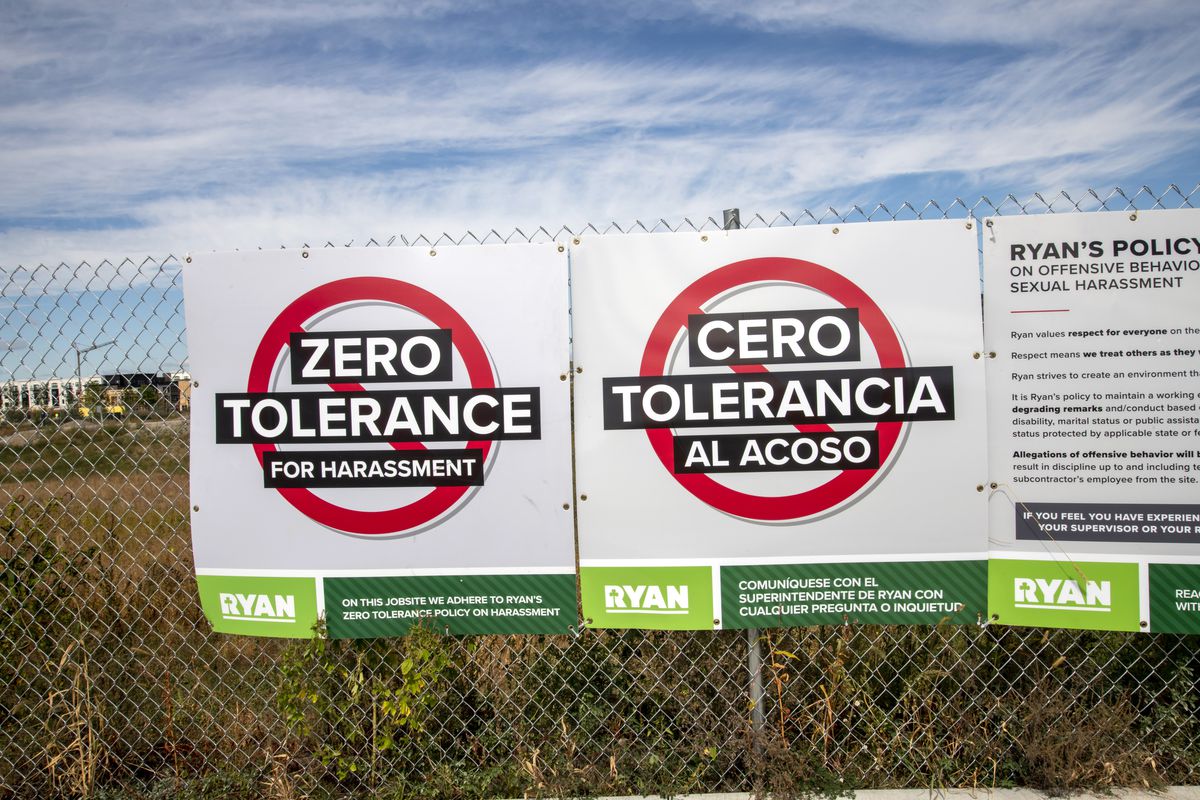 Zero tolerance harassment sign at construction site in Spanish and English.