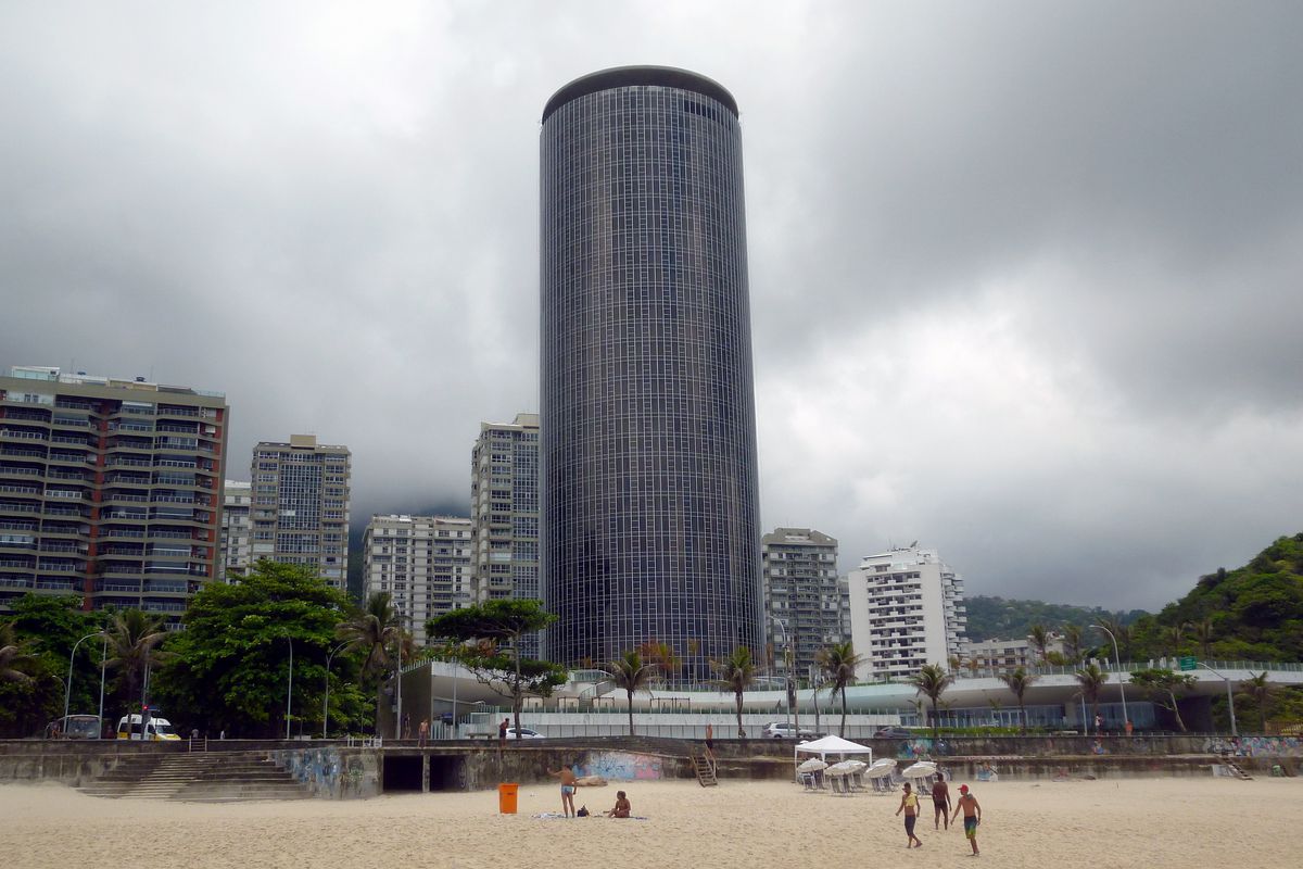 Clouds gather over a cylindrical glass-and-steel tower in Rio de Janeiro, designed by Brazilian architect Oscar Niemeyer.