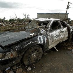 A destroyed police car sits among the debris of tornado-ravaged homes Tuesday, May 21, 2013, in Moore, Okla. A huge tornado roared through the Oklahoma City suburb Monday, flattening an entire neighborhoods and destroying an elementary school with a direct blow as children and teachers huddled against winds. (AP Photo/Charlie Riedel)