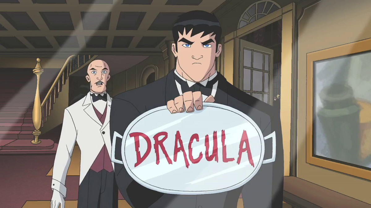 Bruce Wayne holds up a glass platter to a mirror, reflecting the word “Dracula.” Alfred Pennyworth looks on in astonishment.