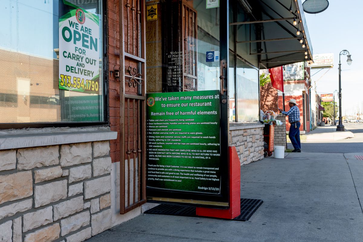A green sign on the open door to El Nacimiento in Detroit.