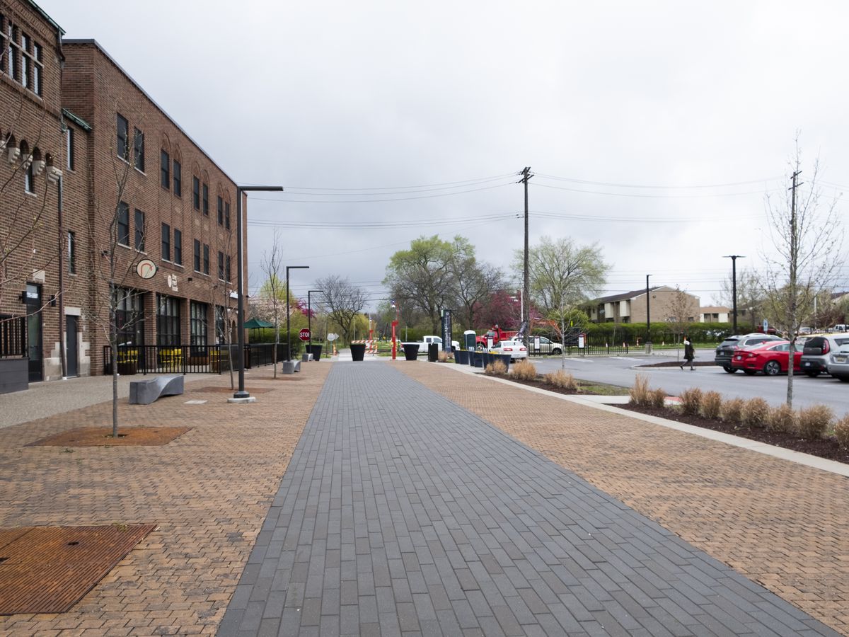 A brick-lined pathway facing a parking lot and a red brick building in Detroit, Michigan.