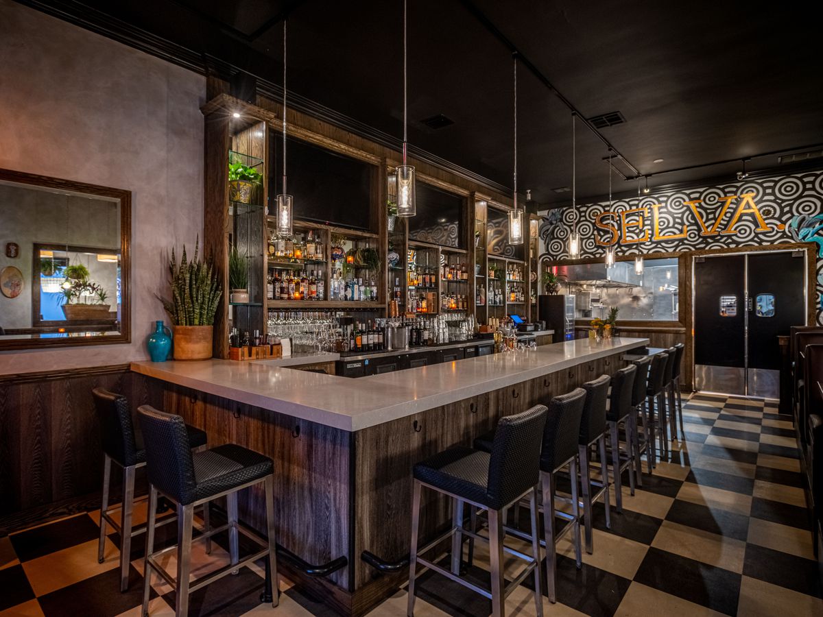 A corner peek into a bar with checkered tile flooring at Selva restaurant in Long Beach, California.