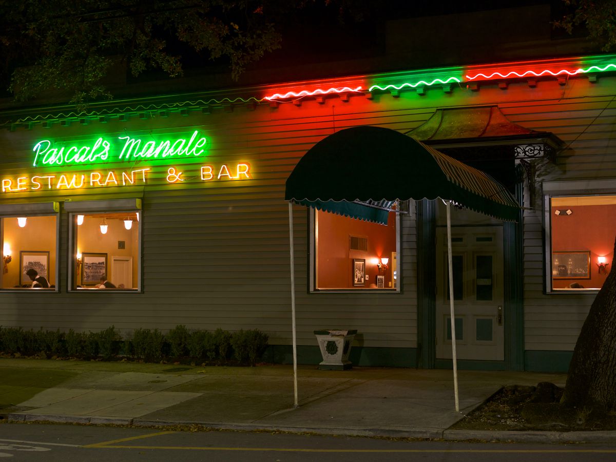 A nighttime street view of Pascal’s Manale Restaurant, name spelled in neon lights.