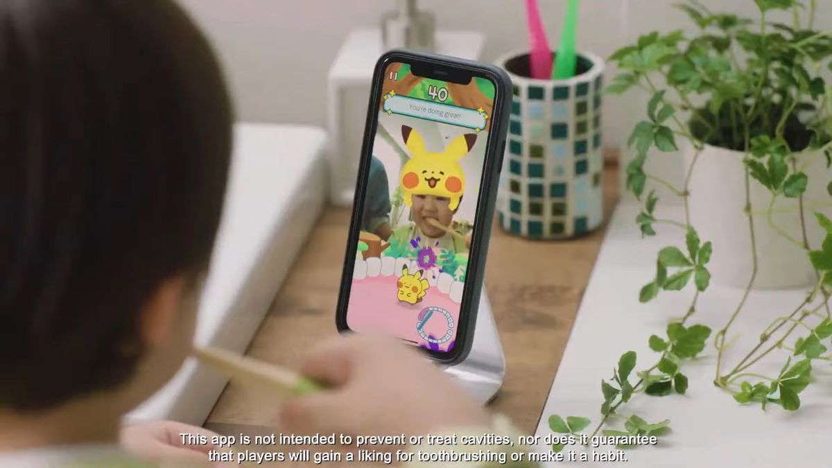 A child brushes his teeth while using the front-facing camera of a phone to play Pokémon Smile