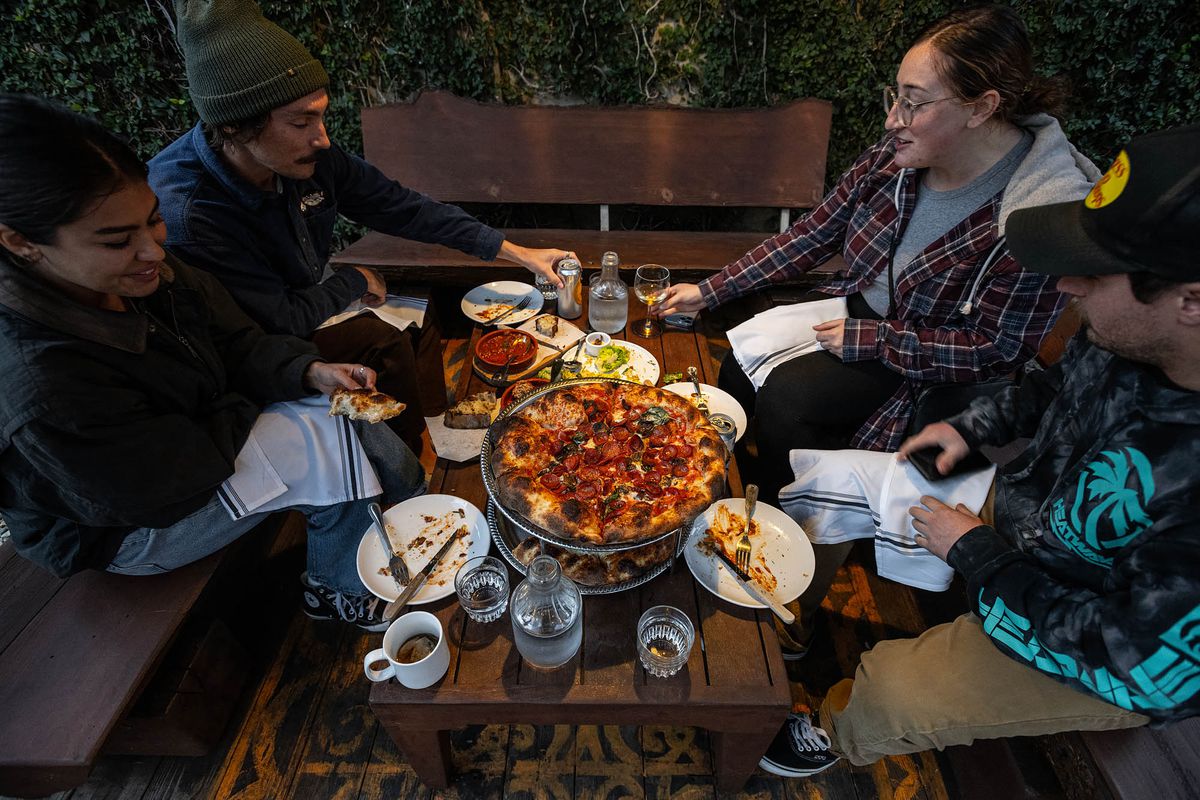 Four people sitting at a wooden table at a pizza restaurant in Orange County, California.