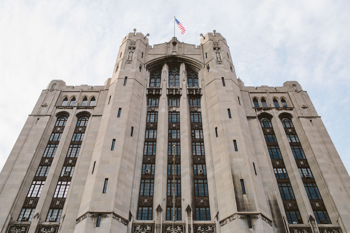 The exterior of the Masonic Temple in Detroit. The facade is tan and there are multiple windows. There is a flagpole on top of the building with a United States flag.