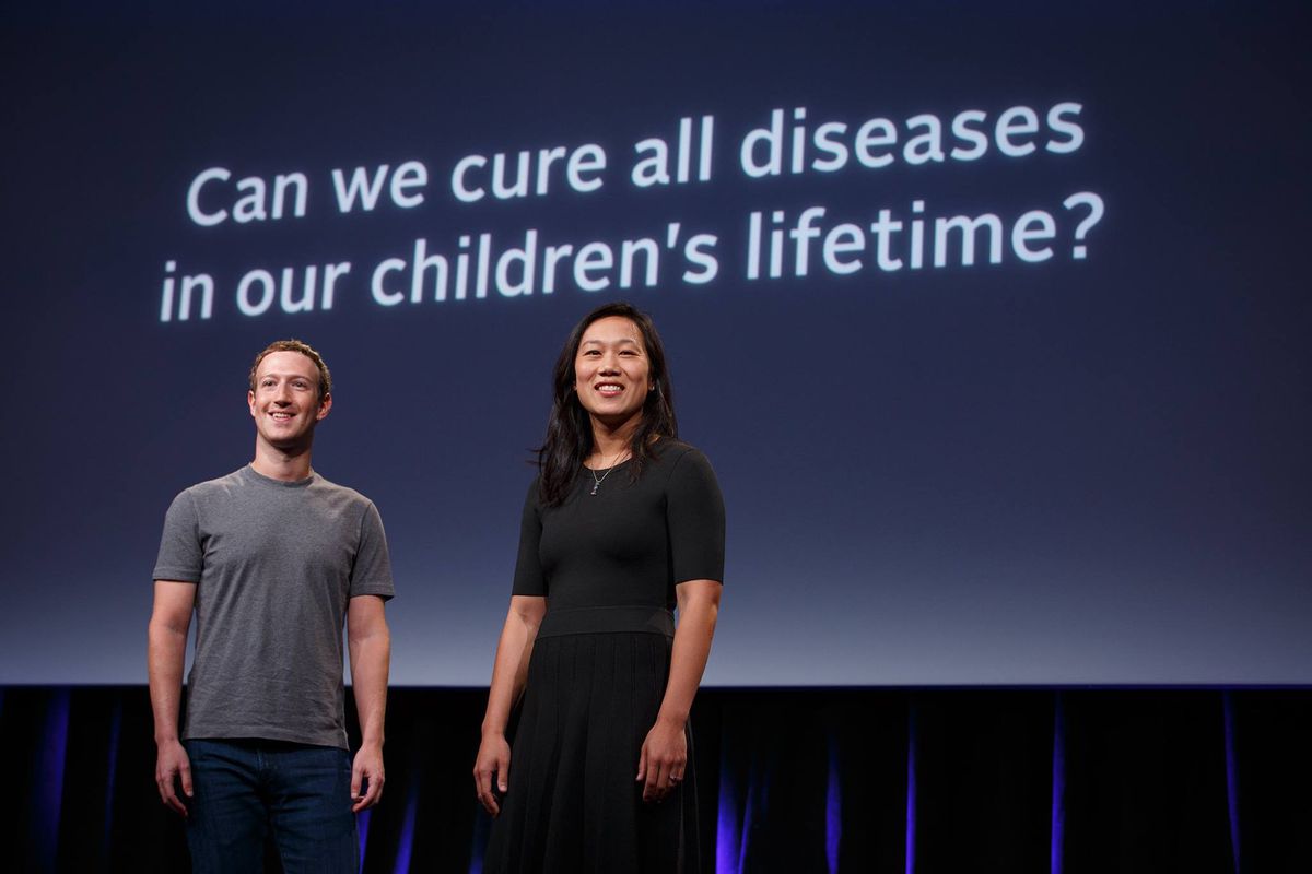 Mark Zuckerberg and Priscilla Chan stand smiling onstage in front of a slide reading “Can we cure all diseases in our children’s lifetime?”