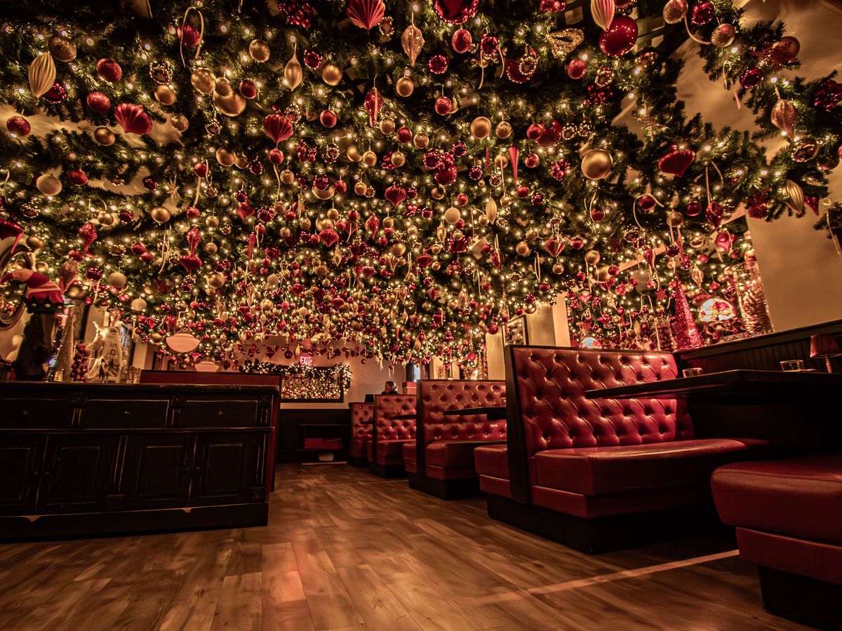 Thousands of holiday ornaments and branches of greenery are strung from the ceiling inside a restaurant dining room.