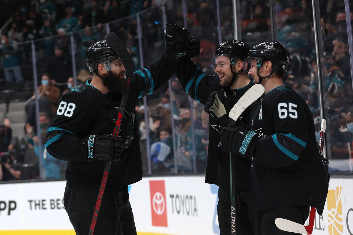 Tomas Hertl #48 of the San Jose Sharks is congratulated by Brent Burns #88 and Erik Karlsson #65 after he scored the winning goal on Felix Sandstrom #32 of the Philadelphia Flyers in overtime at SAP Center on December 30, 2021 in San Jose, California.