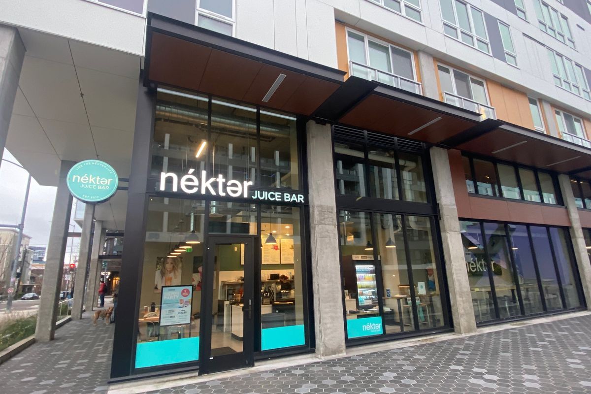 A storefront with large glass windows and a stylized sign that says Nekter Juice Bar.