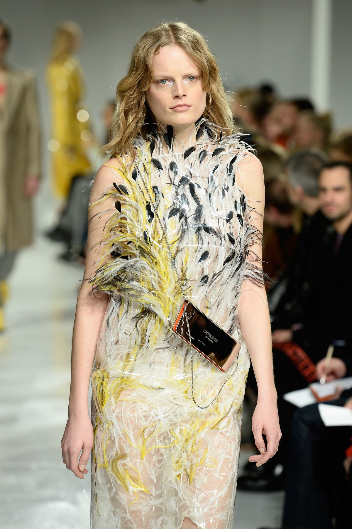 A model wears a yellow, white, and black feathered dress.