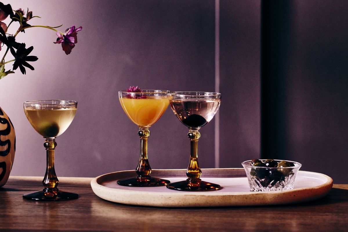Cocktails on a marble tray against in lavender-colored wall.