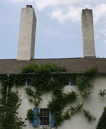 Two matching column like chimney designs on the roof of a house. 