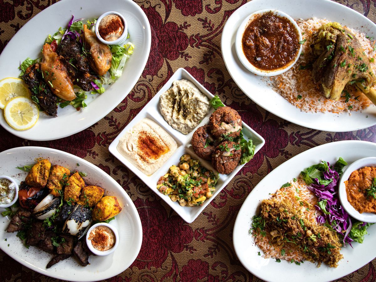A plate of lamb shank, meze, and other dishes on a table at Dar Salam in Portland, Oregon.