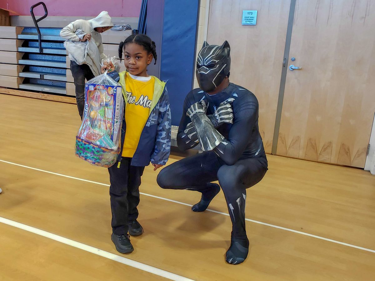 A girl poses with Black Panther at an Easter basket giveaway in Englewood. | Nader Issa/Sun-Times