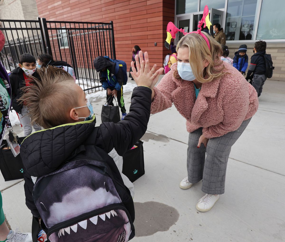 Meadowlark Elementary student Owen Currier, left, high-fives Amy Haran after she gave him a food bag at the school in Salt Lake City on Thursday, Dec. 16, 2021. USANA’s management team delivered 385 two-week food bags for elementary students who will be out of school for the holiday break.