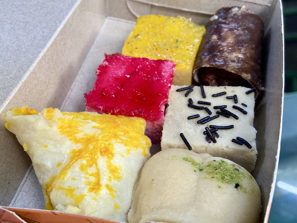 A box of sandesh in a variety of shapes and colors. 