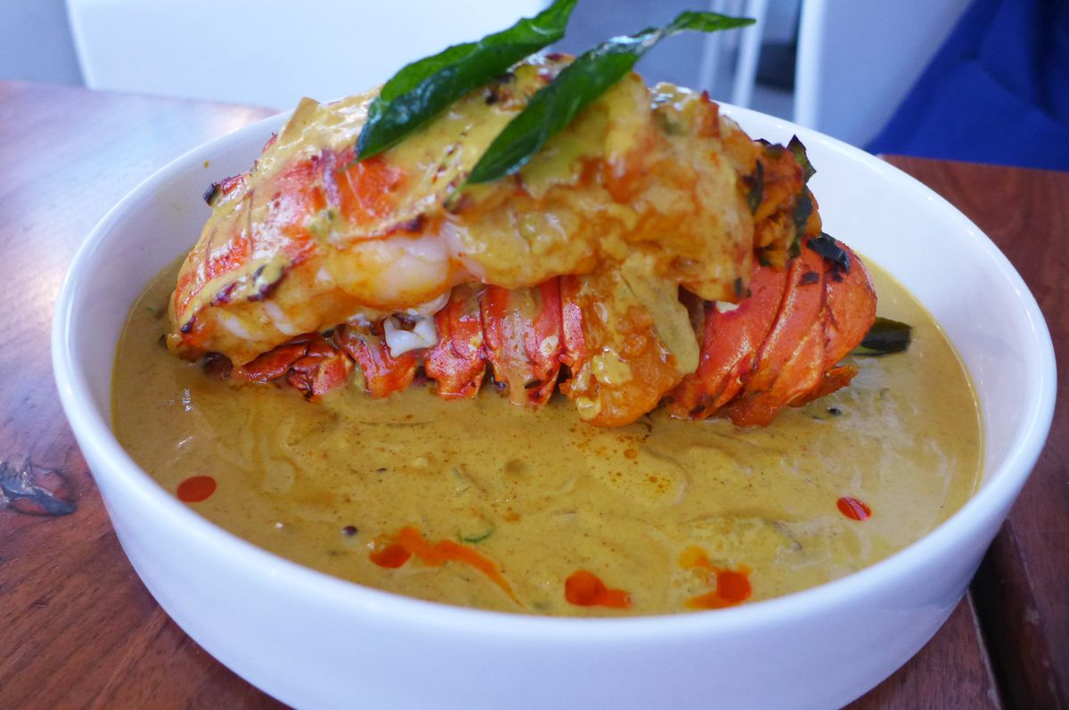 A lobster tail sits in a thick gravy on top of its own removed shell.