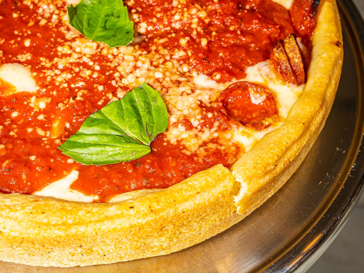 A deep dish pizza topped with pepperoni and basil