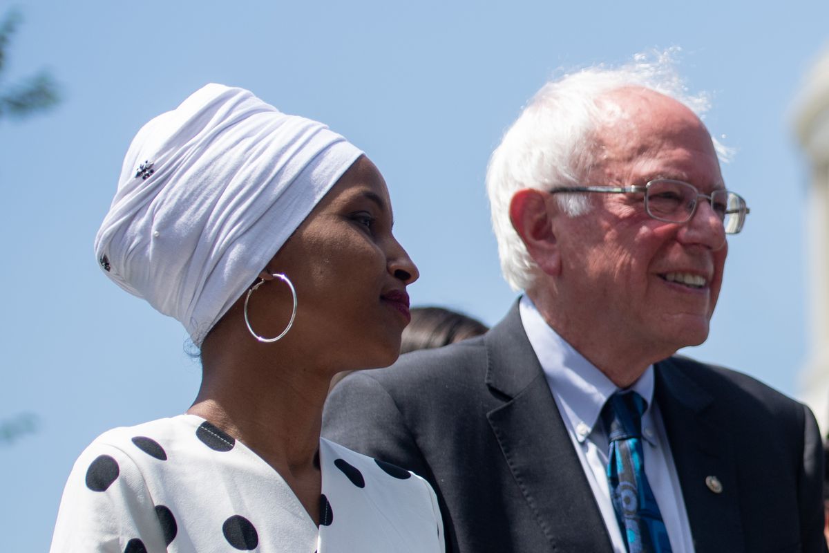 Ilhan Omar and Bernie Sanders standing outside.