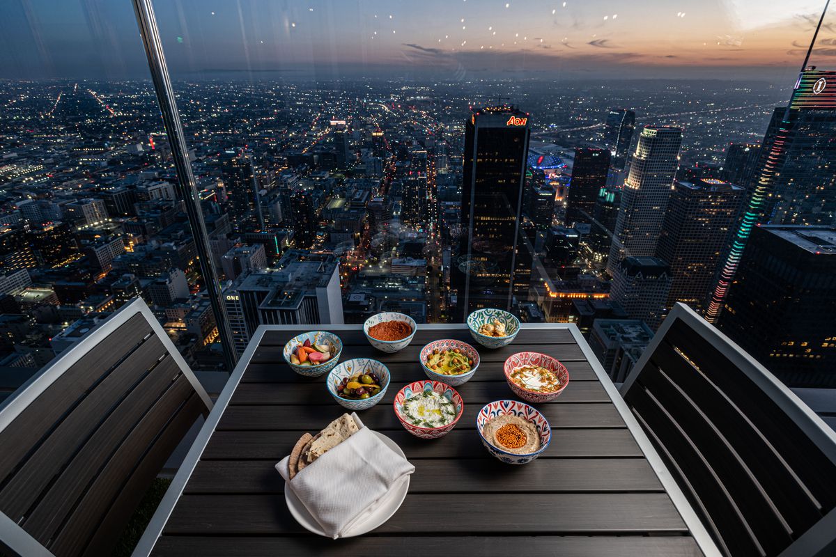 A table set against a thick pane of glass above a twinkling city.