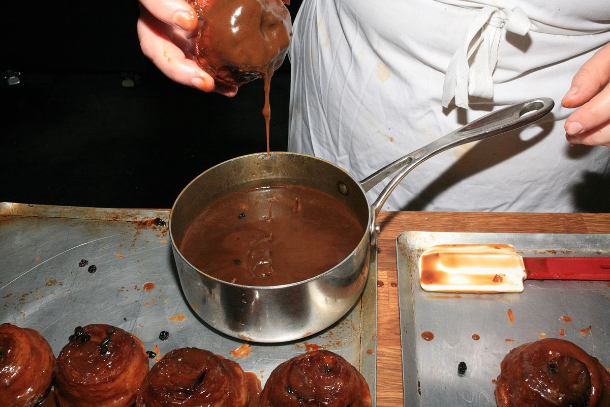 A lardy bun being dunked in a pan of hot spiced caramel