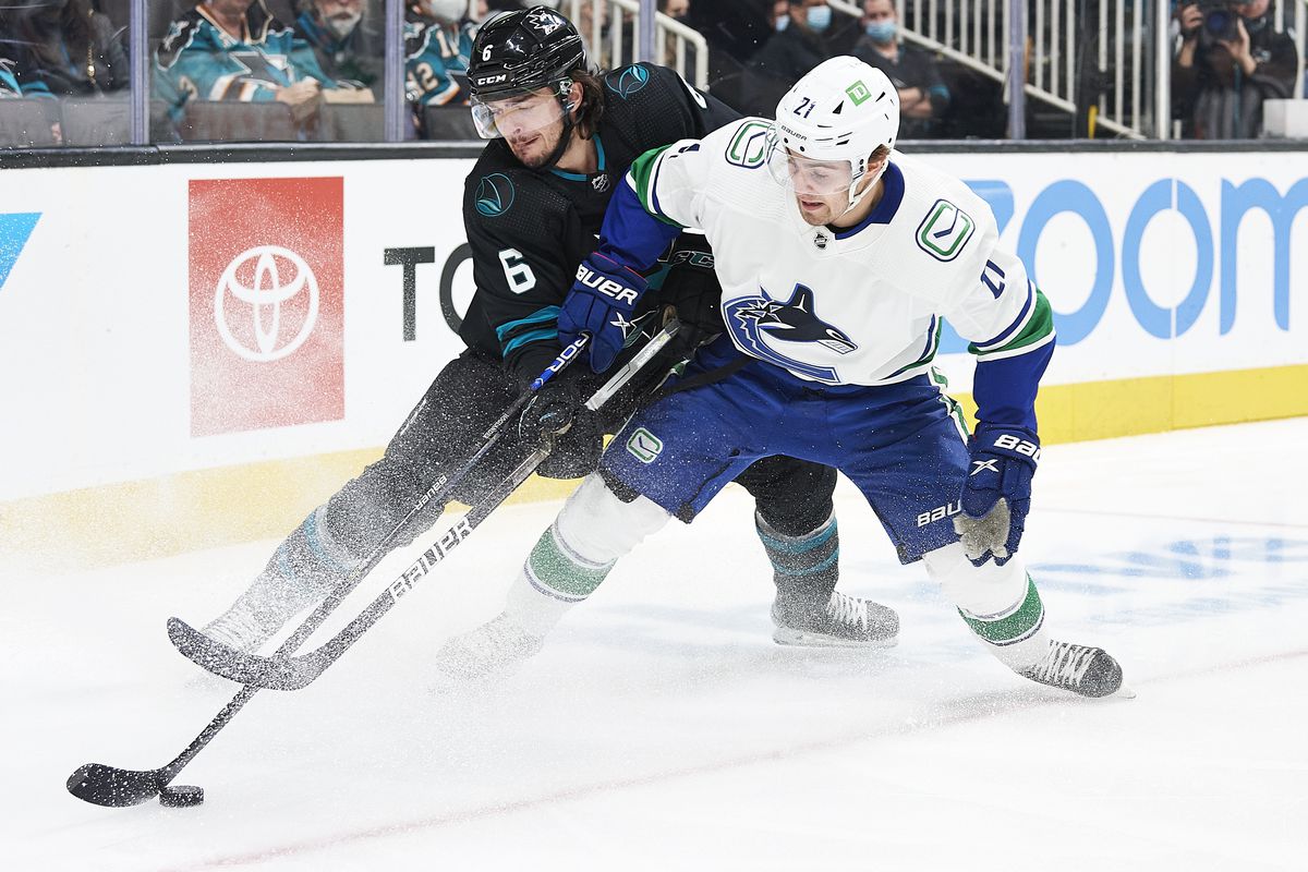 San Jose Sharks defenseman Ryan Merkley (6) and Vancouver Canucks left wing Nils Hoglander (21) battle for the puck during the NHL game on February 17, 2022 at SAP Center in San Jose, CA.