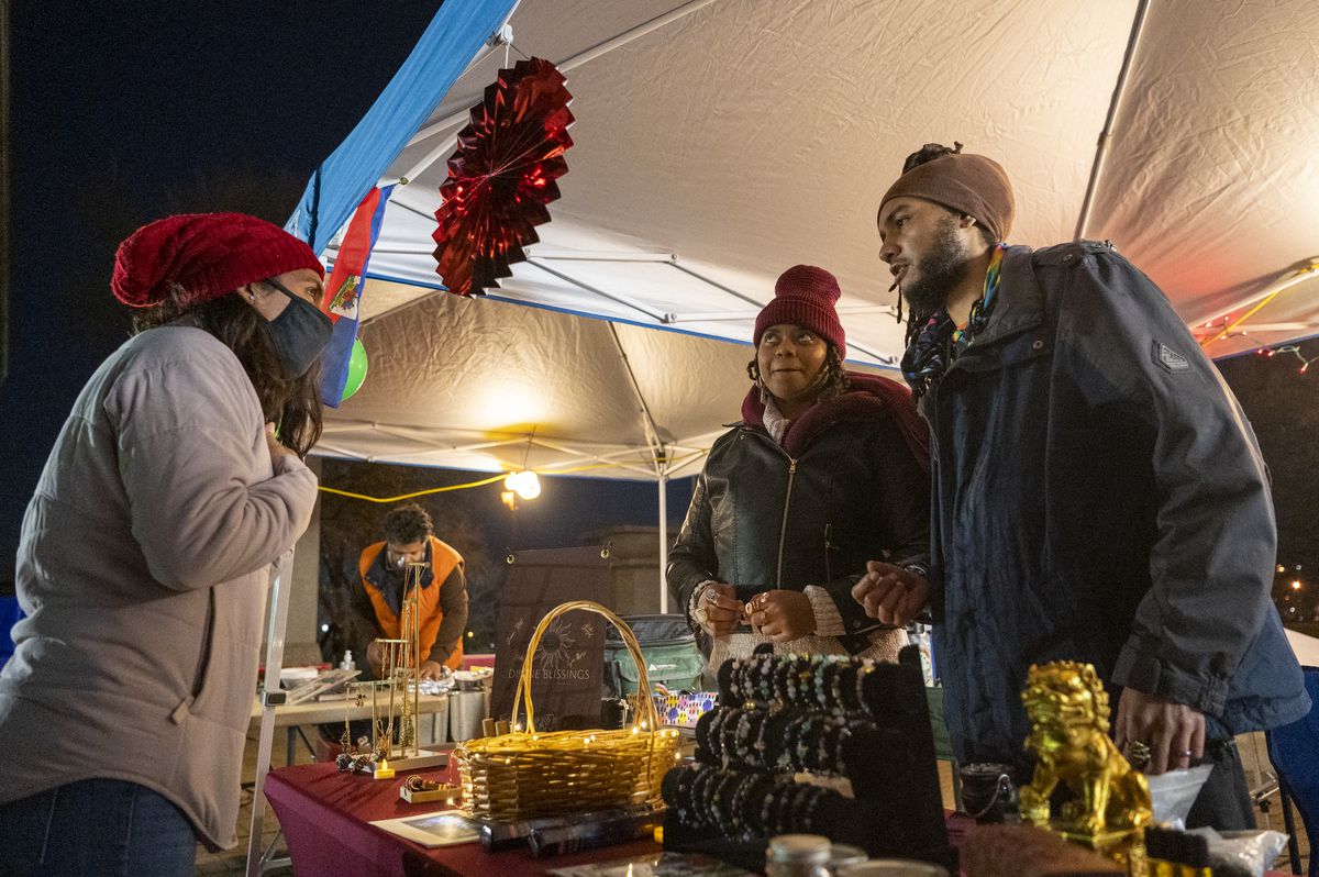 Tyni Simpson (center) and Sahat Votan (left), owners of Divine Blissings, discuss incense with a customer on Friday night at the Humboldt Park boathouse. Their business was among the vendors at a Latino centered Christkindlmarket-type event.