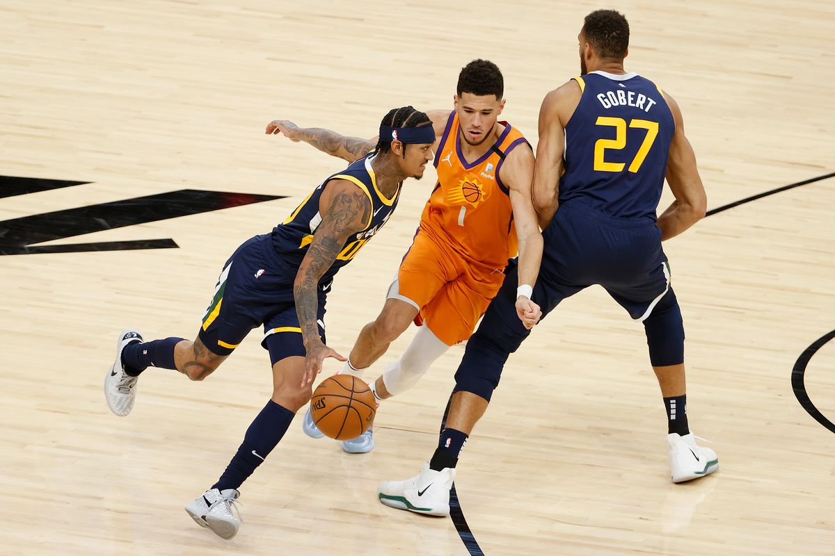 Jordan Clarkson of the Utah Jazz moves the ball past Devin Booker of the Phoenix Suns during the second half of the NBA game at Phoenix Suns Arena on April 30, 2021 in Phoenix, Arizona.&nbsp;