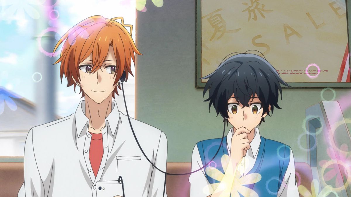 An orange-haired anime boy shares his headphones with a black-haired anime boy aboard a train with flower graphics in the corners of the screen.