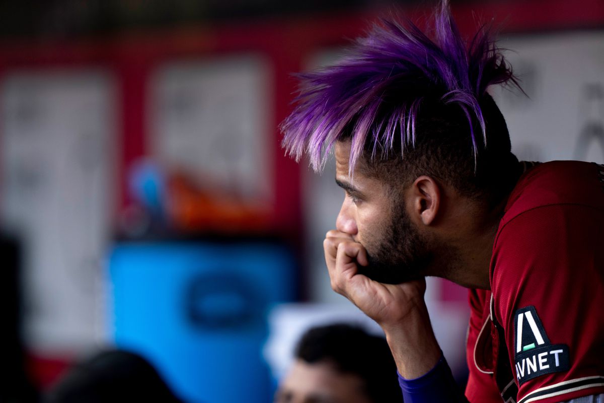 Gurriel Jr. sit pensively in the visitor’s dugout at Great American Ball Park with his purple hair teased up, resting his chin in his hand, staring at something in the distance