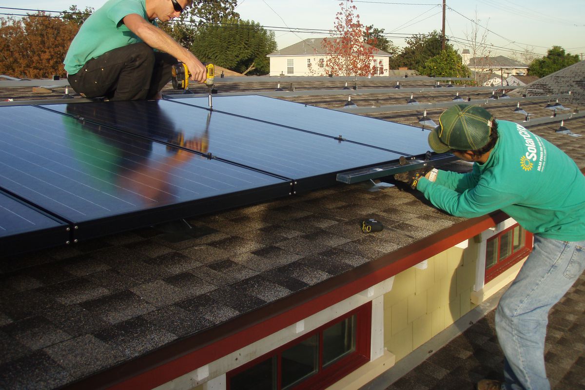 Workers with solar city install rooftop panels in California.