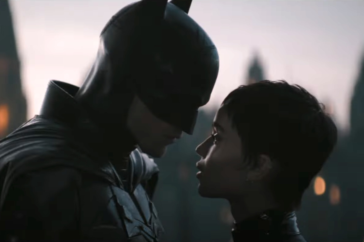 Batman (Robert Pattinson) and Catwoman (Zoë Kravitz) stand intimately close in The Batman. 