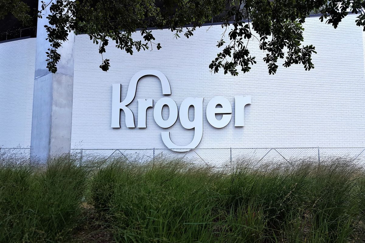 A picture of a new white Kroger logo hung on a white brick wall in front of the Beltline.